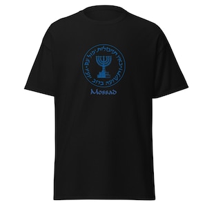 May include: Black t-shirt with a blue emblem featuring Hebrew text and a menorah. The word "Mossad" is printed below the emblem. The shirt is made of a soft material.