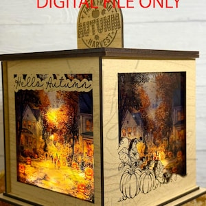 May include: A wooden autumn-themed lantern with a warm, inviting glow. The lantern features a cutout design of pumpkins and a street scene with jack-o'-lanterns. The text "Hello Autumn" and "Autumn Harvest" are visible.