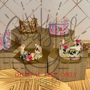 May include: Five different patterned resin bracelets displayed on hexagonal wooden stands. The bracelets feature floral, geometric, and abstract designs in various colors.