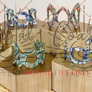 May include: Five different patterned resin bracelets with a geometric design. The bracelets are displayed on wooden stands. The text "Coastal" is written in the background.
