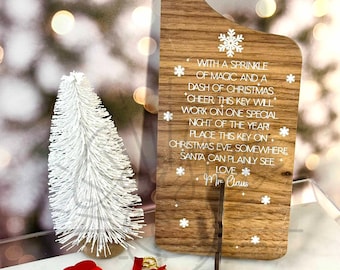 May include: A wooden door hanger with a keyhole and a white snowflake design. The hanger has a message that reads "With a sprinkle of magic and a dash of Christmas cheer this key will work on one special night of the year! Place this key on Christmas Eve somewhere Santa can plainly see. Love, Mr. Claus". A small red velvet bag with a gold key and a wooden tag that reads "Santa's Magic Key" is also pictured.
