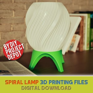 May include: A white spiral-shaped lamp with a green base. The lamp has a unique design with curved lines. The base has three legs. The lamp is on a dark surface with books in the background.