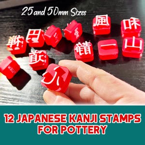 May include: Red Japanese Kanji stamps for pottery in 25mm and 50mm sizes. The stamps feature white Kanji characters. The image also includes the text "12 Japanese Kanji Stamps for Pottery".