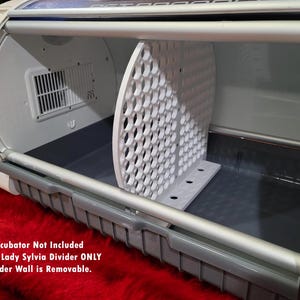 May include: White plastic divider for an incubator. The divider is shaped like a half-circle and has many small holes. The divider is removable. "Incubator Not Included Foster Lady Sylvia Divider ONLY Divider Wall is Removable."