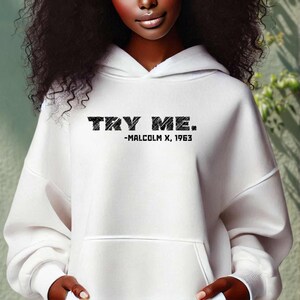 May include: White hooded sweatshirt with the text "TRY ME." and "MALCOLM X, 1963" printed on the front.