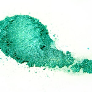 Puede incluir: Primer plano de un montón de polvo de mica verde azulado. El polvo es brillante y tiene un brillo metálico.