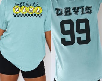 May include: Two light blue t-shirts. The first shirt has the text "Softball Mama" with three yellow softball graphics. The second shirt has the text "Davis 99".