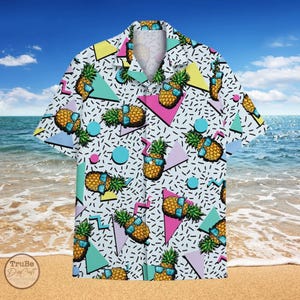May include: A white button-up shirt with a retro 80s pattern featuring pineapples wearing sunglasses. The pattern is on a white background with black, pink, blue, and yellow geometric shapes.