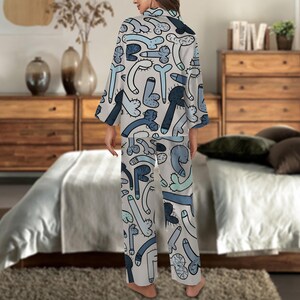 May include: Light gray pajama set with a repeating pattern of blue and black phallus illustrations. The set includes a long-sleeved top and matching pants. The pajamas are made of a soft, lightweight fabric.