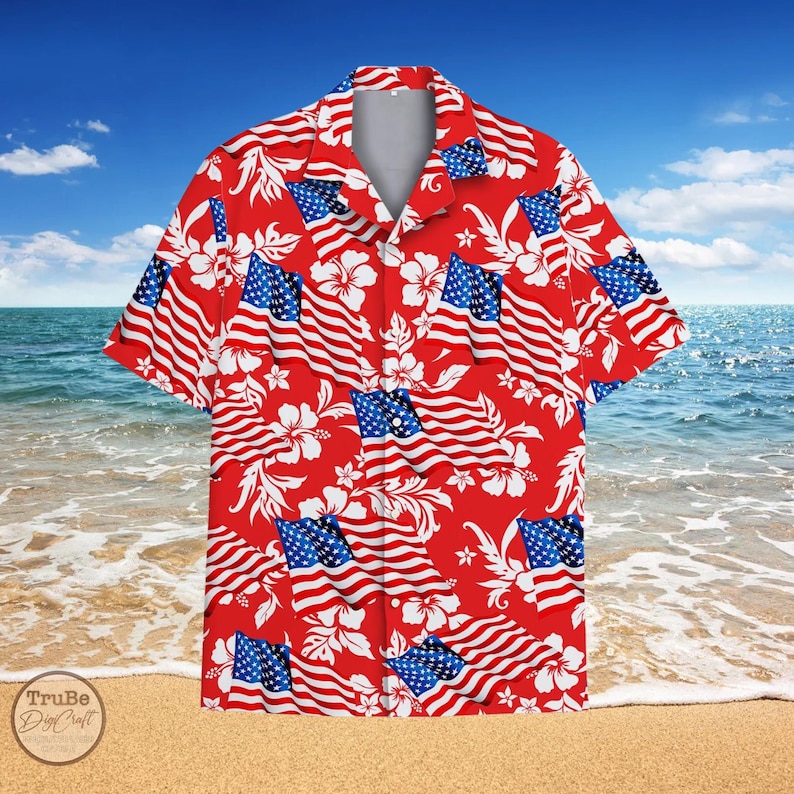 K&ouml;nnte beinhalten: Ein rotes, kurz&auml;rmeliges Hemd mit Kn&ouml;pfen und einem Muster aus wei&szlig;en Hibiskusbl&uuml;ten und amerikanischen Flaggen.