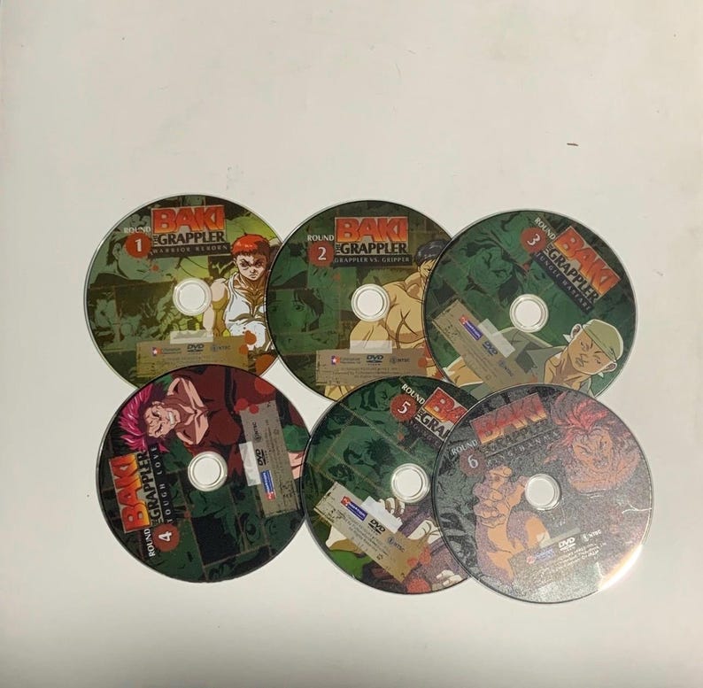 May include: Six DVDs of the anime series "Baki the Grappler." Each disc has a green and brown design with character illustrations and the series title. The discs are numbered 1 to 6.