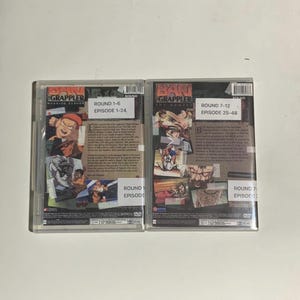 May include: Two DVD cases for the anime series "Baki the Grappler." The first case is labelled "Round 1-6, Episode 1-24." The second case is labelled "Round 7-12, Episode 25-48." Both cases feature colourful illustrations of characters.