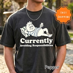 Op de afbeelding: Een witte keramische mok met een zwart handvat en de tekst "But First, Coffee" in een vetgedrukte, zwarte letter. De mok staat op een houten oppervlak. De mok is ongeveer 10 cm hoog.