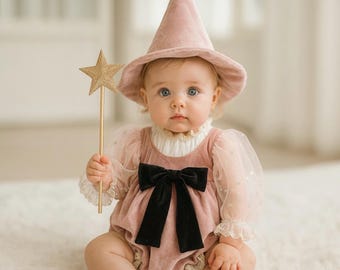 May include: A dusty pink velvet pointed hat and a matching velvet romper with sheer puff sleeves, a high ruffled collar, and a large black velvet bow at the center. A gold glitter star wand is held in one hand, completing the ensemble.
