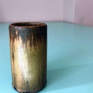 May include: A brown and gold ceramic vase with a textured surface.