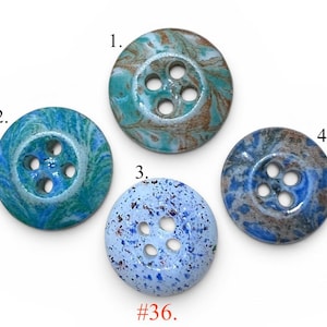 May include: Four round buttons labeled 1 through 4, each featuring four holes. Button 1 has a teal and brown marbled pattern. Button 2 shows a blue and green swirl. Button 3 is light blue with dark speckles. Button 4 has a blue and grey mottled finish. #36.