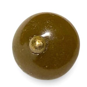 Può includere: Primo piano di un oggetto rotondo verde oliva con un piccolo pomello dorato sulla parte superiore. L'oggetto ha una finitura lucida e sembra essere fatto di un materiale solido. Lo sfondo è bianco.