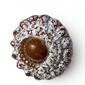 Può includere: Pomello decorativo maculato marrone e bianco, con un elemento centrale arrotondato marrone scuro. Il pomello ha una forma organica e strutturata, su sfondo bianco. Adatto per mobili o decorazioni.