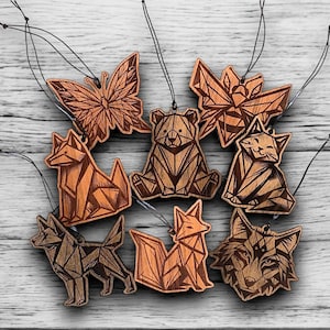 May include: A selection of wooden animal ornaments, featuring a butterfly, bear, cat, fox, and wolf. Each ornament is intricately cut with geometric designs and has a string for hanging. The ornaments are a warm brown colour.