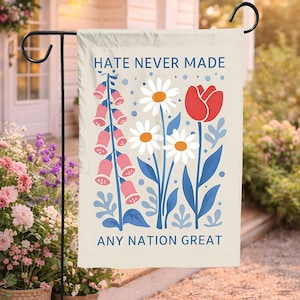 Könnte beinhalten: Eine beige Gartenflagge mit dem Text "HATE NEVER MADE ANY NATION GREAT" und einem floralen Design. Das Design umfasst rosa Fingerhutblumen, weiße Gänseblümchen und eine rote Tulpe mit blauen Blättern.