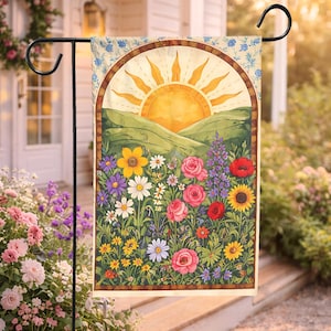 May include: A garden flag featuring a vibrant floral design with a rising sun over rolling green hills. The flag showcases a variety of colorful flowers, including roses, daisies, and sunflowers, set against a cream-colored background.