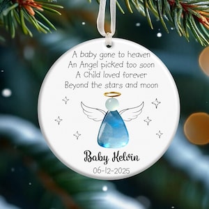 May include: White round Christmas ornament with a blue angel design and the text "A baby gone to heaven, An Angel picked too soon, A Child loved forever, Beyond the stars and moon." The ornament also includes the name "Baby Kelvin" and the date "06-12-2025."