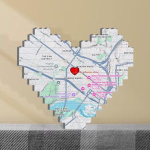 Op de afbeelding: Een hartvormige kaart van Richmond, Virginia, met een rood hart dat een locatie markeert. De kaart bevat straatnamen, bezienswaardigheden en de tekst "THE FAN DISTRICT" en "JACKSON WARD". De kaart is gemaakt van rechthoekige blokken.