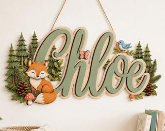 Può includere: Una targa decorativa in legno da parete con il nome Chloe in grandi lettere corsive color verde salvia. La targa è decorata con una volpe arancione dipinta, pini verdi, un piccolo uccellino blu, una farfalla rosa, pigne e funghi, appesa con una corda.