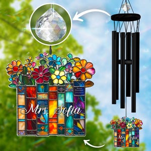 May include: A stained glass wind chime featuring a colorful floral design atop a stack of books. The books are inscribed with the name "Mrs. Sofia". A clear crystal prism hangs above the floral design and a set of black chimes.