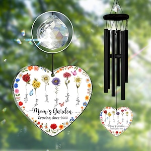 May include: A heart-shaped Mom's Garden ornament with colorful flowers and names, hanging with a crystal and black wind chimes. The text reads "Growing since 2000."
