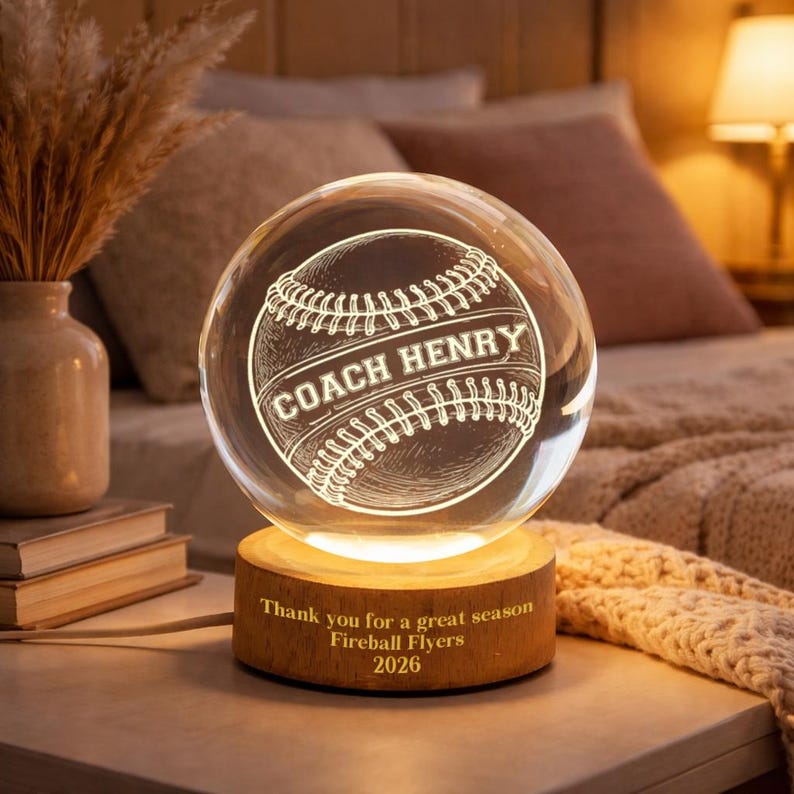 May include: A baseball-themed crystal ball night light with the text "COACH HENRY" etched on the baseball design. The wooden base has the inscription "Thank you for a great season Fireball Flyers 2026".