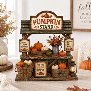 Könnte beinhalten: Ein dekorativer Kürbisstand aus Holz mit abgenutztem grünen Finish, mehreren Miniaturkürbissen und Schildern mit der Aufschrift PUMPKIN STAND, LOCALLY GROWN PUMPKINS, HAPPY FALL Y'ALL und PICK YOUR PERFECT PUMPKIN, inklusive einer kleinen Laterne und Herbstlaub.