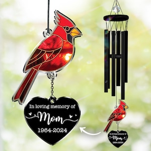 May include: A red cardinal wind chime with a black heart-shaped pendant that reads "In loving memory of Mom 1964-2024." The cardinal is made of stained glass and has a black and silver frame. The wind chime has black chimes.