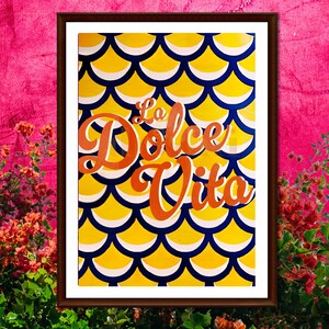 May include: A framed print with a yellow and blue geometric pattern. The text "La Dolce Vita" is written in orange cursive letters.
