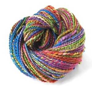 May include: A vibrant ball of yarn in a spectrum of colors, including blue, green, purple, and orange. The yarn appears thick and textured, ideal for knitting or crocheting projects. The yarn is tightly wound, showcasing the various hues.
