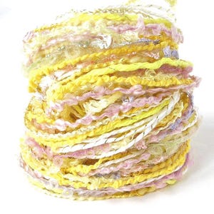 May include: A vibrant skein of yarn in shades of yellow, pink, and white. The yarn has a textured, multi-strand design with metallic silver accents. Ideal for knitting, crocheting, or other fiber art projects.