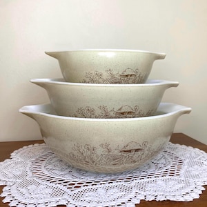 Peut inclure: Ensemble de trois bols à mélanger Pyrex vintage. Les bols beiges ont une finition mouchetée et un motif marron de champignons et de feuillage. Chaque bol a des poignées.