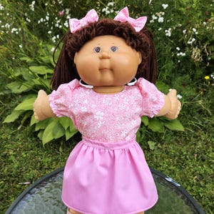 Muñeca Cabbage Patch de 16 a 18 pulgadas con falda rosa, camisa y lazos para el cabello.