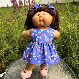 Muñeca Cabbage Patch de 16 a 18 pulgadas con vestido morado, bragas y coleteros.