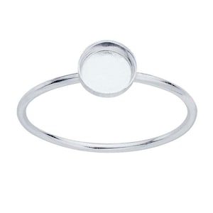 May include: A silver ring with a round, open bezel setting. The bezel is smooth and has a polished finish.