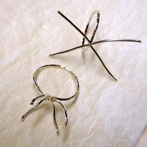 May include: Two silver ring settings for jewelry making. One setting is a round bezel with prongs, the other is a six-prong setting.