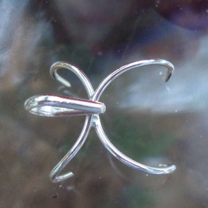 May include: A silver-toned metal pendant with a unique, multi-pronged design. The pendant has a loop at the top for attaching to a chain or cord.