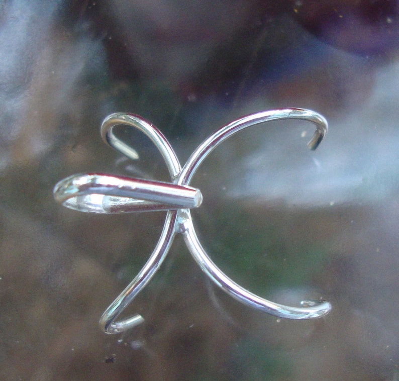 May include: A silver-toned metal pendant with a unique, multi-pronged design. The pendant has a loop at the top for attaching to a chain or cord.