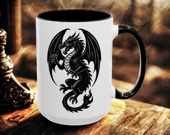 May include: A white ceramic mug with a black interior and a black handle. The exterior features a detailed black graphic illustration of a winged dragon with a long, curled tail, depicted in a side profile with its mouth open.