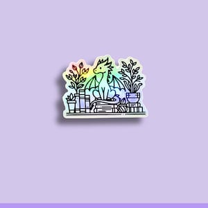 May include: A holographic vinyl sticker featuring a cartoon dragon sitting among plants and books. The dragon has a rainbow-colored wing and is surrounded by potted plants and stacks of books. The text "WATERPROOF VINYL STICKER" is at the bottom.
