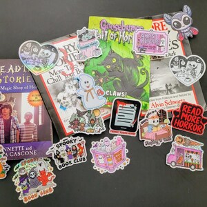 May include: A collection of stickers and books with a spooky theme. The stickers feature ghosts, bats, and other Halloween-related imagery. The books include titles like "Deadly Stories" and "Goosebumps".
