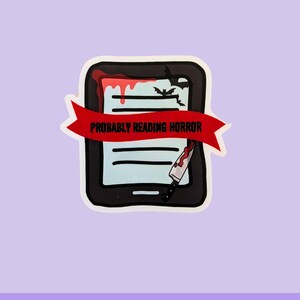 May include: A waterproof vinyl sticker featuring a black e-reader with a red banner that reads "Probably Reading Horror." The e-reader has a bloody design with a knife and bats.