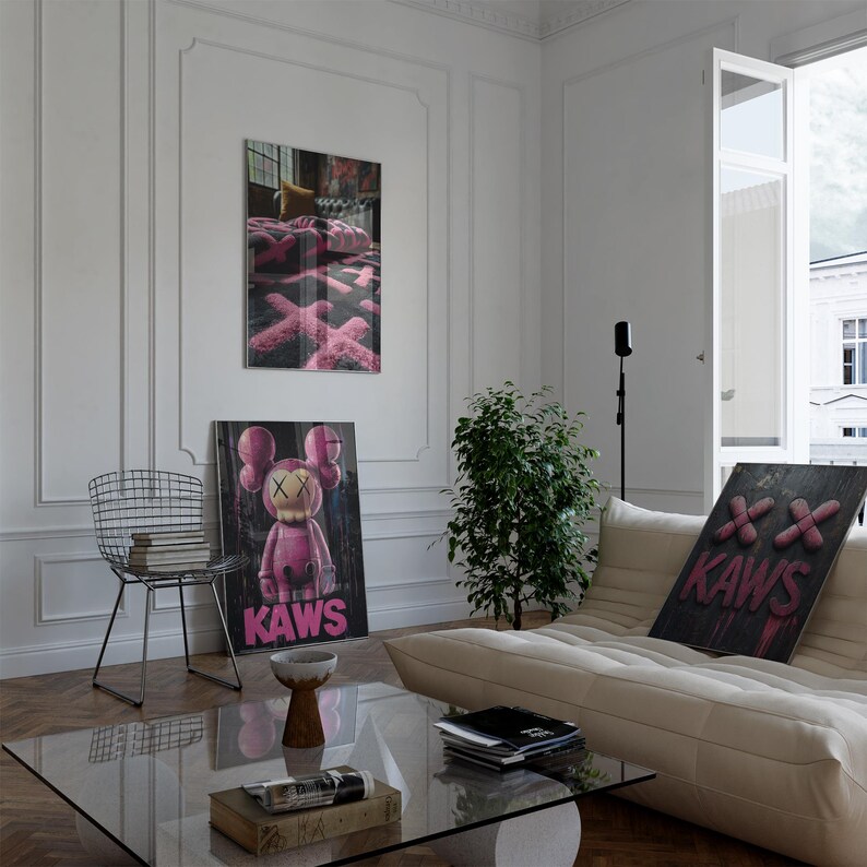 May include: An interior shot featuring modern art prints and a minimalist aesthetic. The artwork includes a pink KAWS figure and abstract designs. A wire chair, glass coffee table, and a beige sofa complete the contemporary living space.