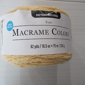 May include: A ball of light yellow Macrame Colors yarn. The label reads "Pattern Included" and "Limited Time Only." It contains 82 yards, 10.5 ounces, 75 metres, and 300 grams of yarn. The yarn is for macrame projects.
