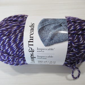 May include: A skein of Loops & Threads Impeccable acrylic yarn. The yarn is a mix of purple, white, and dark purple. The label shows a knitted item and the text "Impeccable Acrylic". The skein weighs 3 oz and is 180 yards long.